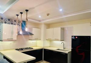 a kitchen with white cabinets and a black refrigerator at Modern City Escape Bahria hieghts in Rawalpindi