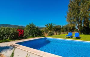 a swimming pool with two blue chairs next to it at Can Bernat in Cala Mendia