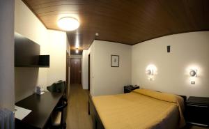 Habitación de hotel con cama, escritorio y escritorio. en Hotel Mirella, en Ponte di Legno