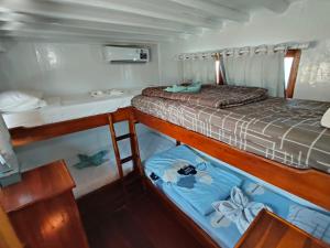 a bedroom with a bed and two bunk beds on a boat at Sharing trip komodo 3d 2n in Labuan Bajo
