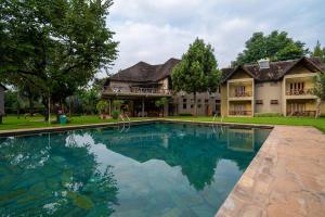 a large swimming pool in front of a house at Weru Weru River Lodge in Moshi