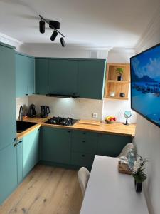 a kitchen with green cabinets and a white table at View Apartments Gorlice in Gorlice