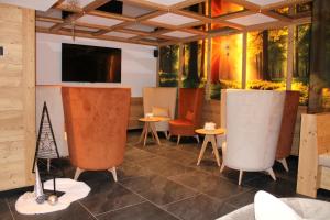 a room with chairs and a flat screen tv at Hotel Villa Cima Undici in Pozza di Fassa