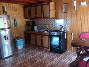 a kitchen with a stove and a refrigerator at Cabaña piedra azul in Dalcahue +33 photos