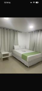 a bedroom with a large bed and a table at Pousada Pergentino in Maceió