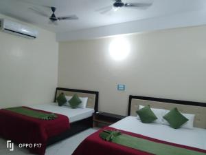 two beds in a room with red and green pillows at Hotel Sunshine in Konārka