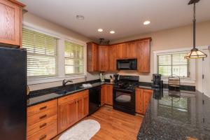 a kitchen with wooden cabinets and black appliances at Bear Foot by Railey Vacations in Oakland +40 photos