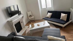 a living room with a blue couch and a tv at La demeure du 159 in Cognac