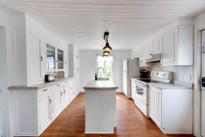 a white kitchen with white cabinets and a kitchen island at Le Toit Rouge - 3457 in Saint-Férréol-les-Neiges