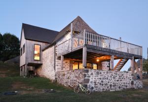 a house with a deck on top of a stone wall at La grange du vezou in Paulhenc