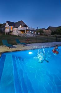 a man in a swimming pool at night at La grange du vezou in Paulhenc