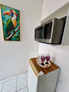 a kitchen with a microwave and a table with wine glasses at Apartamento no Centro in Manaus +7 photos