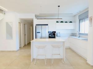 a kitchen with a white island and two bar stools at THE white lotus in Eilat