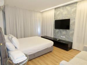 a hotel room with a bed and a flat screen tv at THE white lotus in Eilat