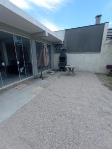 a patio with a table and an umbrella next to a building at Casa 2 quartos a 2 quadras do mar nova in Matinhos