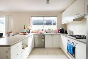 a kitchen with white cabinets and a stove top oven at Comfort Home in Wyndham Vale