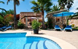 a pool with two chairs and an umbrella and a house at Can Lopez Vara in Campos