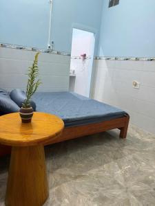 a bed with a blue mattress and a table with a plant at Con Cua Biển Homestay in Tuy Hoa