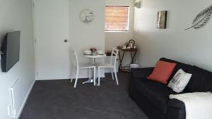 uma sala de estar com um sofá e uma mesa em Jan's Boutique B & B Suite em Christchurch