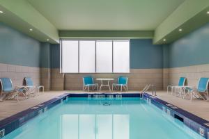 a swimming pool with chairs and a table in a building at Holiday Inn Express Windsor Waterfront by IHG in Windsor