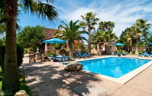 a swimming pool with palm trees and blue umbrellas at Can Lopez Vara in Campos