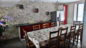 a kitchen with a table with chairs and a refrigerator at Aux P'tits Cabris in Lahayville