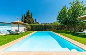 a swimming pool in a yard with two chairs and an umbrella at Es Collet De Manacor in Manacor