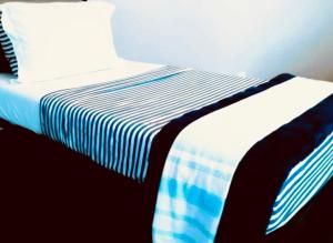 a bed with a blue and white striped sheets and a pillow at House FLL airport in Fort Lauderdale