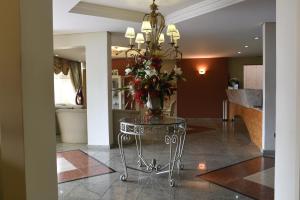 a vase of flowers on a glass table in a hallway at Hotel Santa Fé in Ponta Grossa