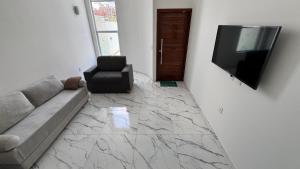 a living room with a couch and a television on a wall at Bela casa jacumã in Conde