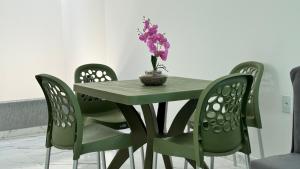 a green table with chairs and a vase with flowers at Bela casa jacumã in Conde