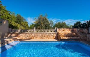 a swimming pool with a stone wall and a fence at Moli De Ca N'orell in Santanyi