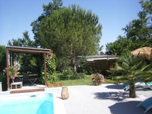 a garden with a swimming pool and a pavilion at Au Fil de l'Eau in La Ronde