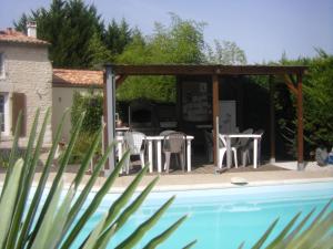 a patio with a table and chairs next to a pool at Au Fil de l'Eau in La Ronde