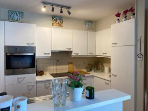 a kitchen with white cabinets and a counter with flowers at Charming Duplex in Knokke-Heist +14 photos