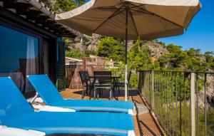 a deck with blue chairs and an umbrella at Amaret in Deia