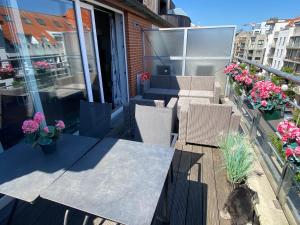 a balcony with two tables and chairs and flowers at Charming Duplex in Knokke-Heist