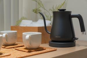 a coffee maker and two cups on a table at 하로스테이 신사점 in Seoul