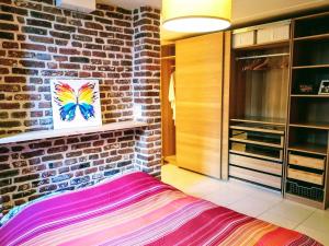 a bedroom with a brick wall and a colorful painting at Au coeur de l'Ardenne - Peaceful loft in Baelen