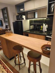 a kitchen with a wooden counter and stools at Premium Apartment in Bagé in Bagé