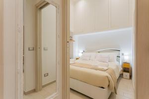 a white bedroom with a bed and a mirror at Il borgo incantato in Bitonto