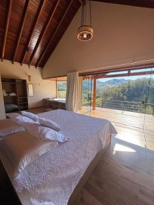 a bedroom with a large bed and a large window at Chalé Pedra Madeira-Recanto Venâncio in São Bento do Sapucaí