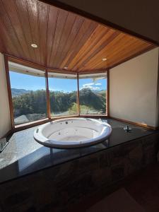 a large tub in a room with a large window at Chalé Pedra Madeira-Recanto Venâncio in São Bento do Sapucaí +18 photos