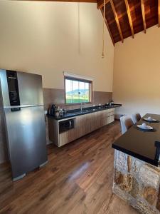 a large kitchen with a stainless steel refrigerator at Chalé Pedra Madeira-Recanto Venâncio in São Bento do Sapucaí