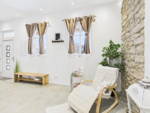 a living room with a rocking chair and windows at Sam's Cottage Suite in Niederweis