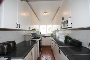 a kitchen with white cabinets and black counter tops at Ash Grove House in Galway
