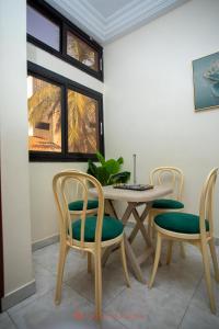 a dining room with a table and four chairs at Cabral residence in Guediawaye +5 photos