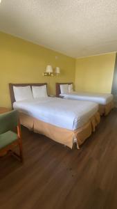 two large beds in a room with a chair at Evergreen Plaza Inn in Metairie