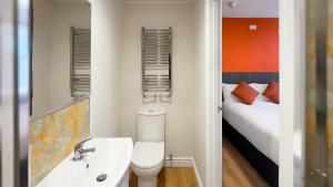 a bathroom with a toilet and a sink and a bed at Thorpe Lodge Hotel in Peterborough +7 photos