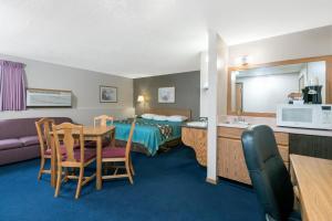 a hotel room with a bed and a table and chairs at Super 8 by Wyndham Milbank SD in Milbank